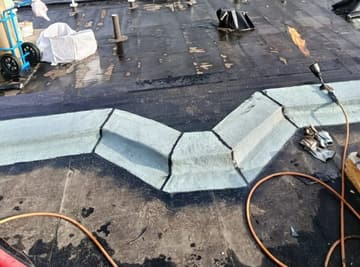 Relevés d'étanchéité en cours de pose sur un chéneau